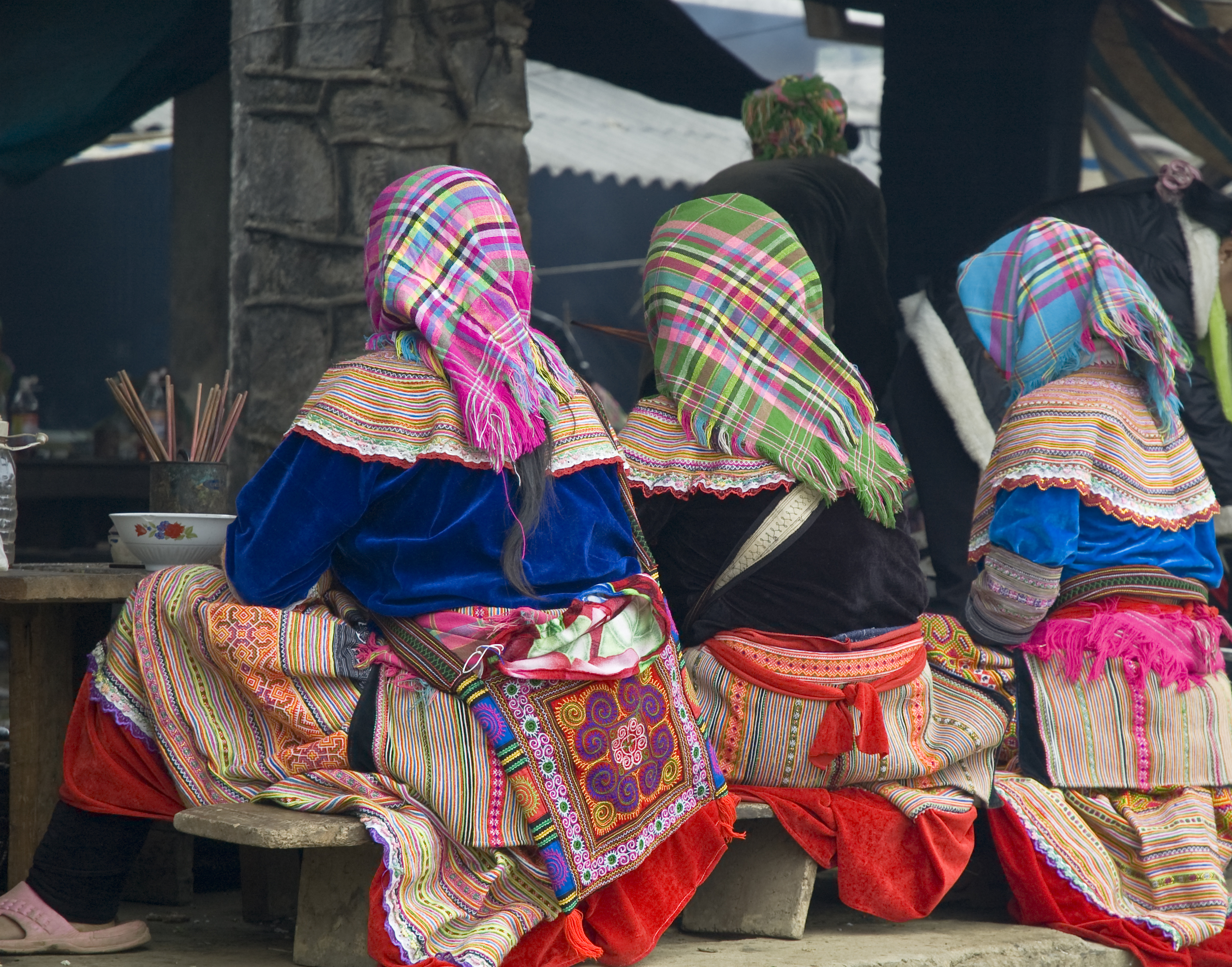 Women sitting with backs to the camera, dining, traditional dress, headscarves