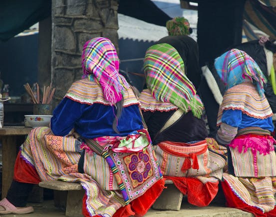 Women sitting with backs to the camera, dining, traditional dress, headscarves