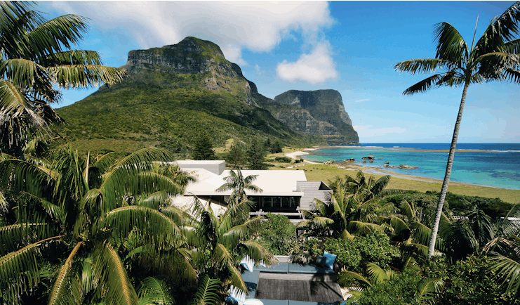 Capella Lodge exterior, modern architexture, exterior seating area, lush greenery, beach and mountains in background
