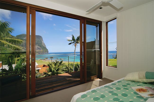 Capella Lodge lagoon loft guestroom, double bed, balcony overlooking bay and coastline