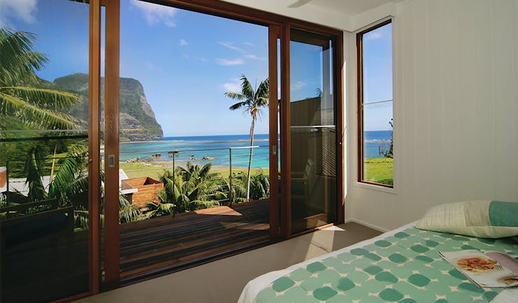 Capella Lodge lagoon loft guestroom, double bed, balcony overlooking bay and coastline