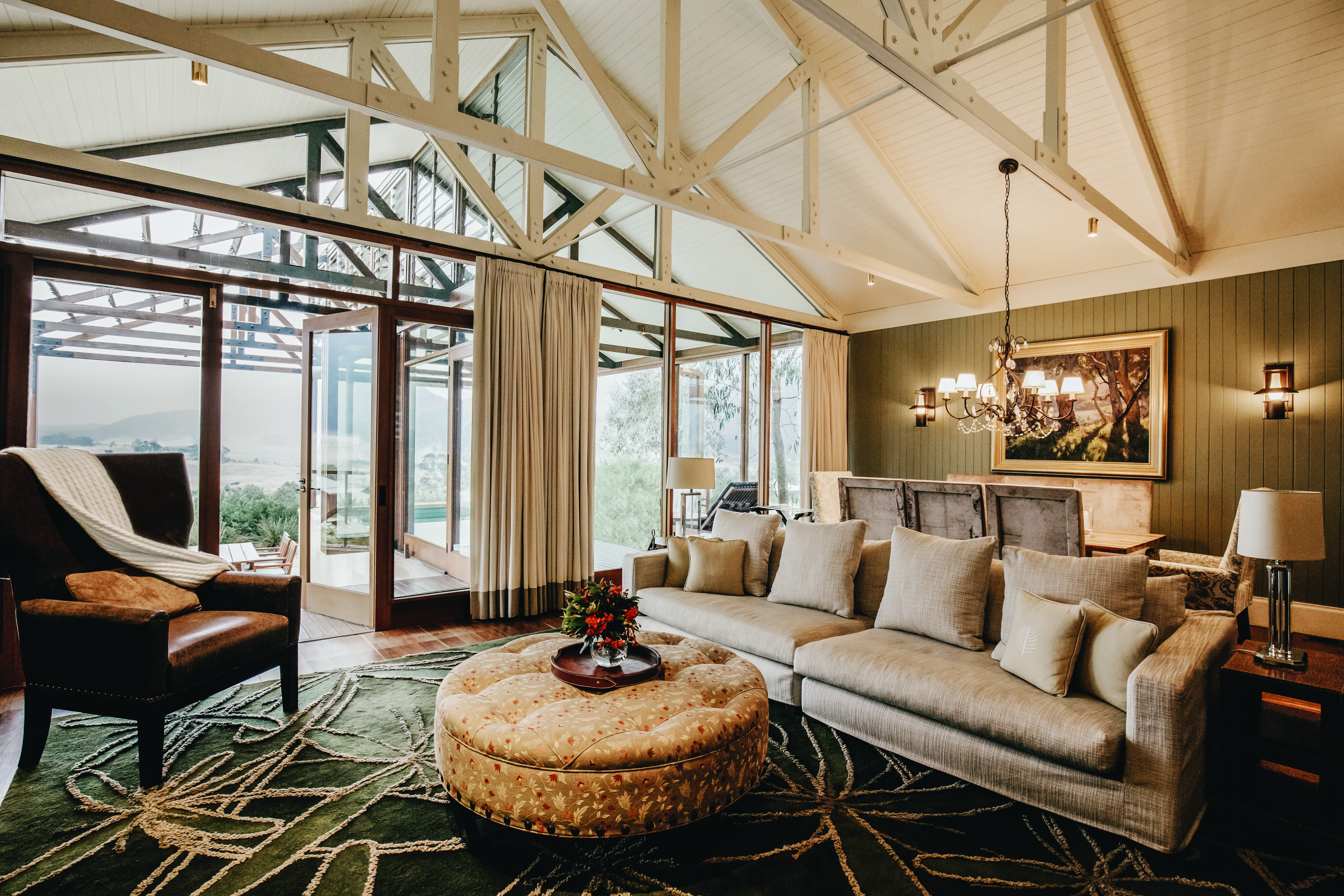 Villa living room area with sofa, wood pannelled ceilings, and doors opening onto a balcony