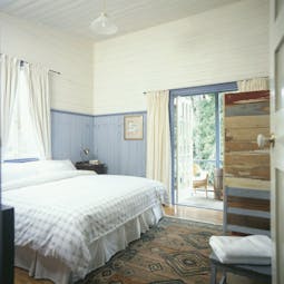 Old Leura Dairy New South Wales workers bedroom with blue and white wooden walls and patio door to balcony