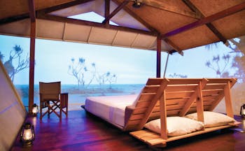 Bamurru Plains lodge interior, double futon bed, netted walls overlooking outback