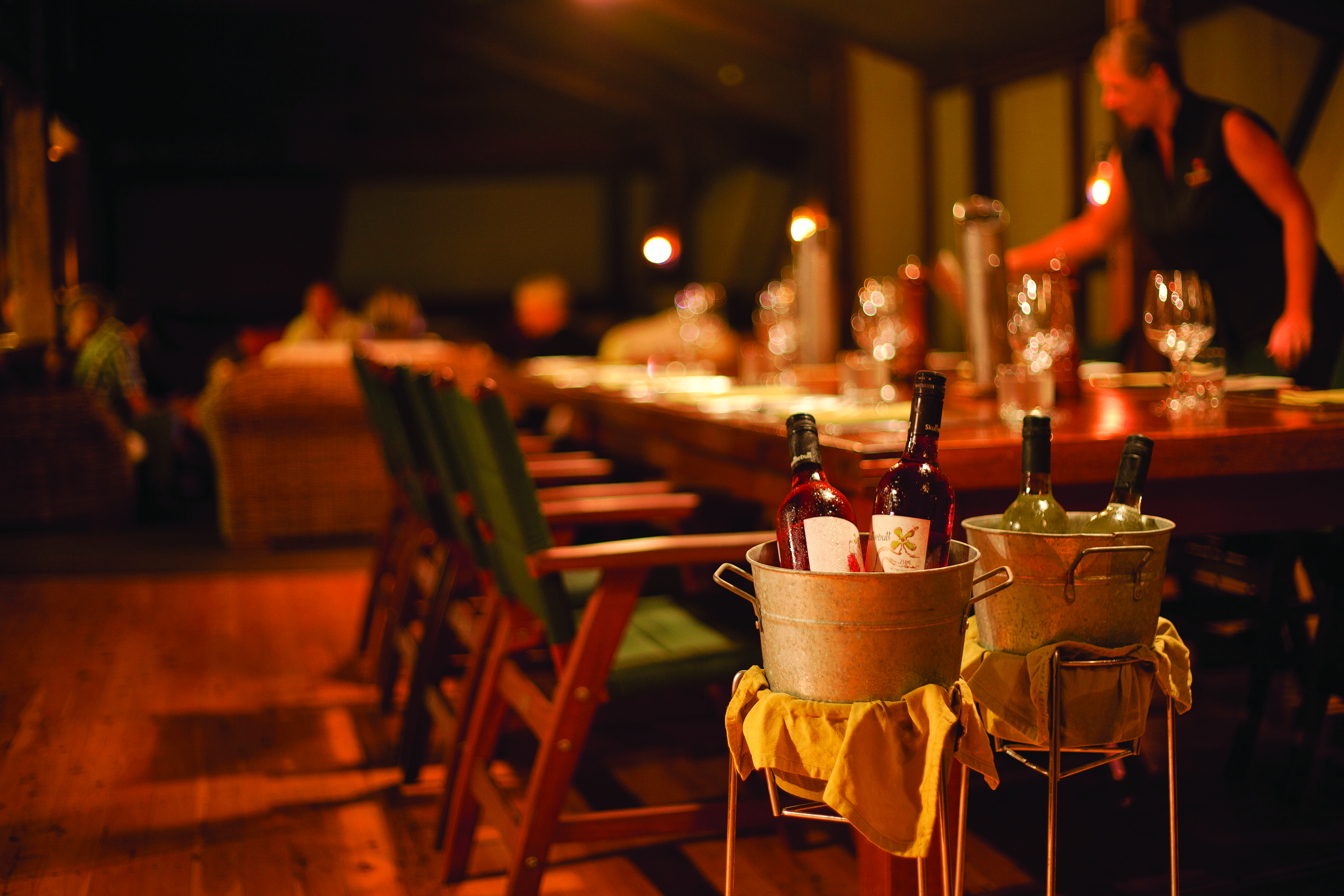 Bamurru Plains restaurant, tables set for eating, waitress, wine in bucket in main focus