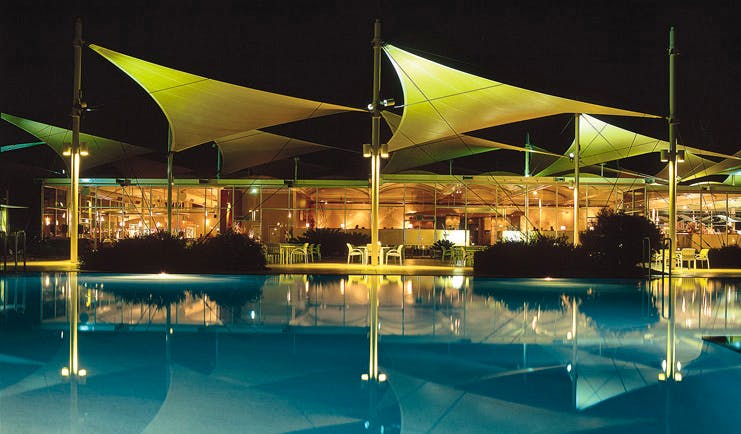 Sails in the Desert Ayers Rock outdoor pool overlooked by glass building with metal sail sculptures