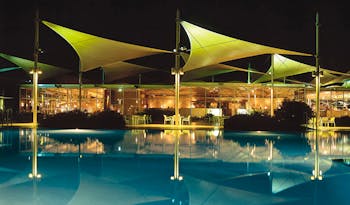 Sails in the Desert Ayers Rock outdoor pool overlooked by glass building with metal sail sculptures