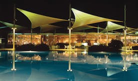 Sails in the Desert Ayers Rock outdoor pool overlooked by glass building with metal sail sculptures