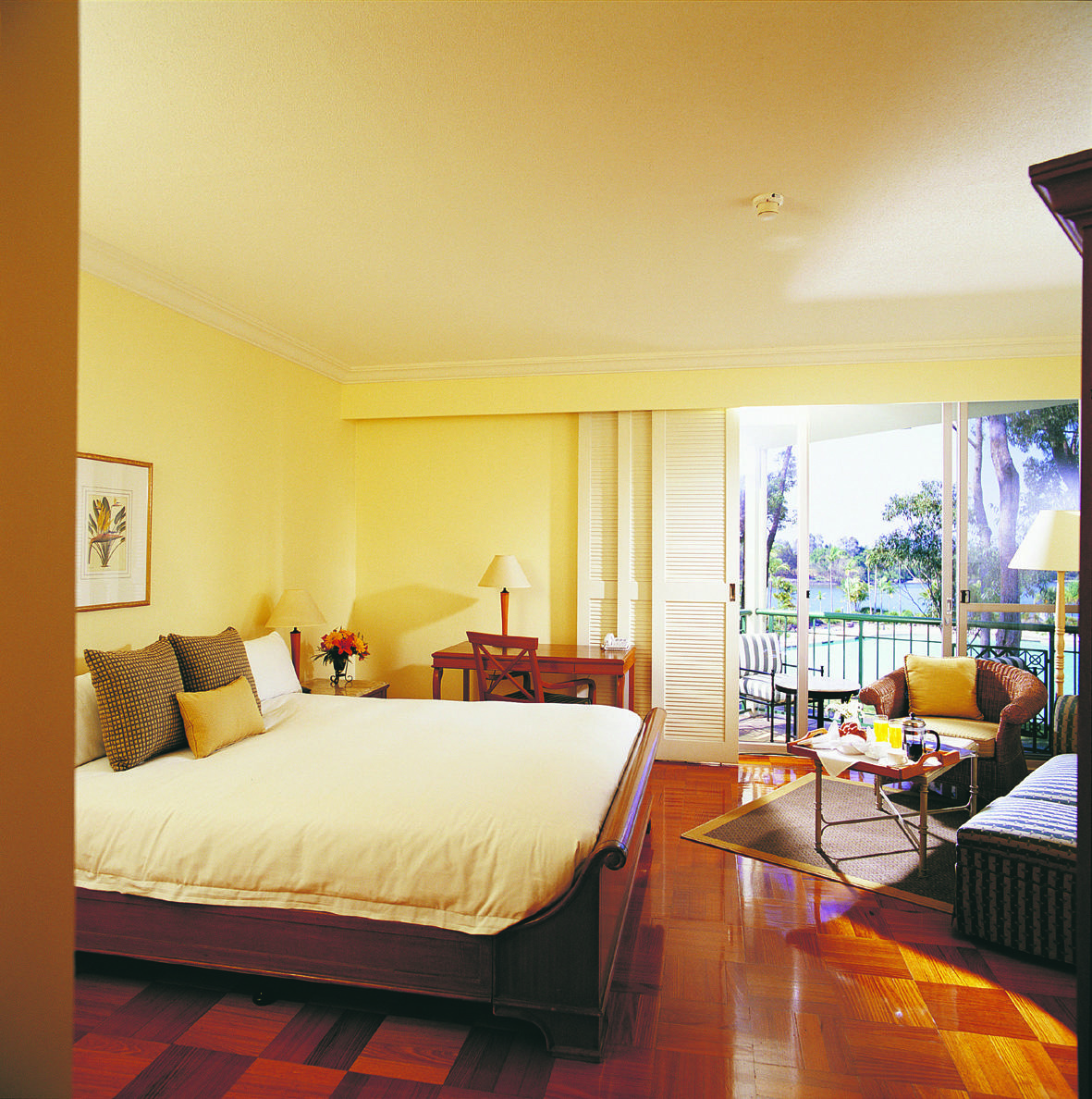 Bedroom with wooden floors, large double bed, and doors opening onto a balcony