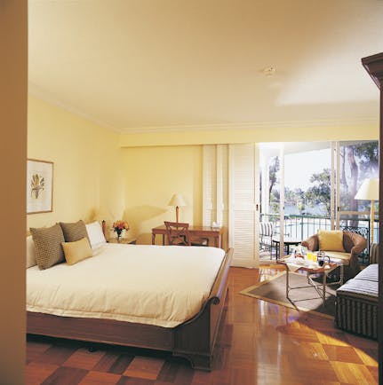 Bedroom with wooden floors, large double bed, and doors opening onto a balcony