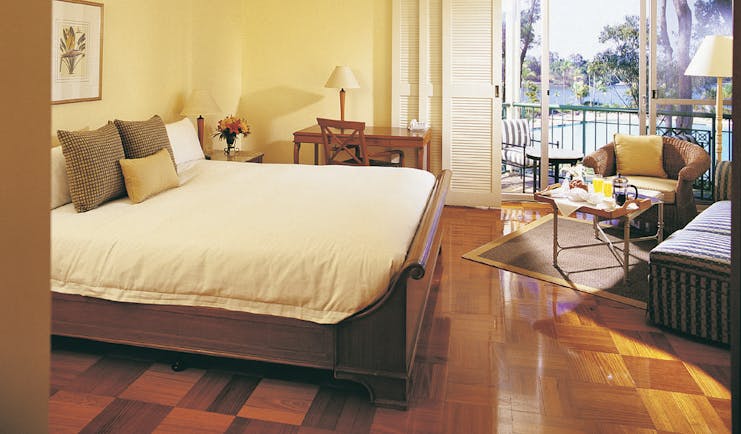 Bedroom with wooden floors, large double bed, and doors opening onto a balcony