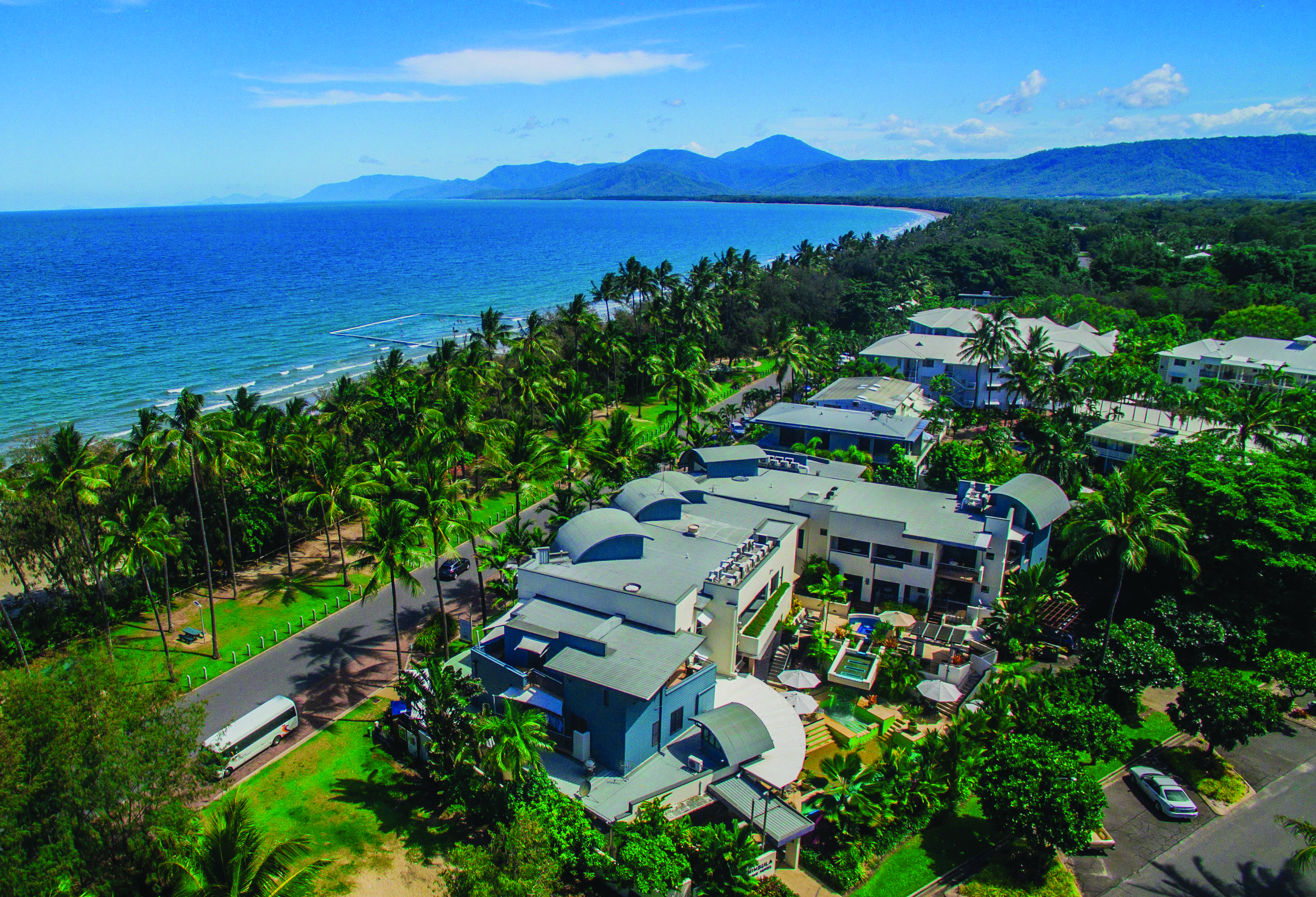 Port Douglas Peninsula Queensland aerial beach view of hotel complex with outdoor pool and palm trees near coast