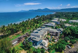 Port Douglas Peninsula Queensland aerial beach view of hotel complex with outdoor pool and palm trees near coast