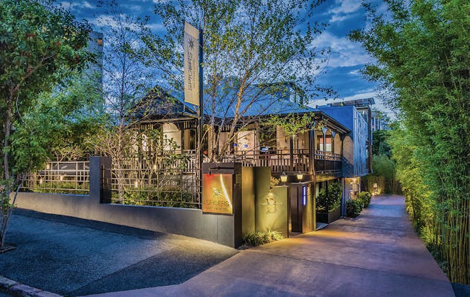 Exterior of hotel with trees surrrounding it and minin lights lighting it up 