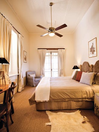 Bedroom with electric overhead fan, large double bed and draping curtains