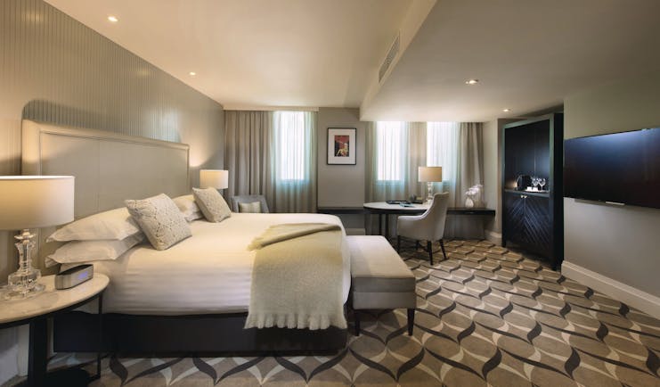 Deluxe king room with large double bed, television and chairs