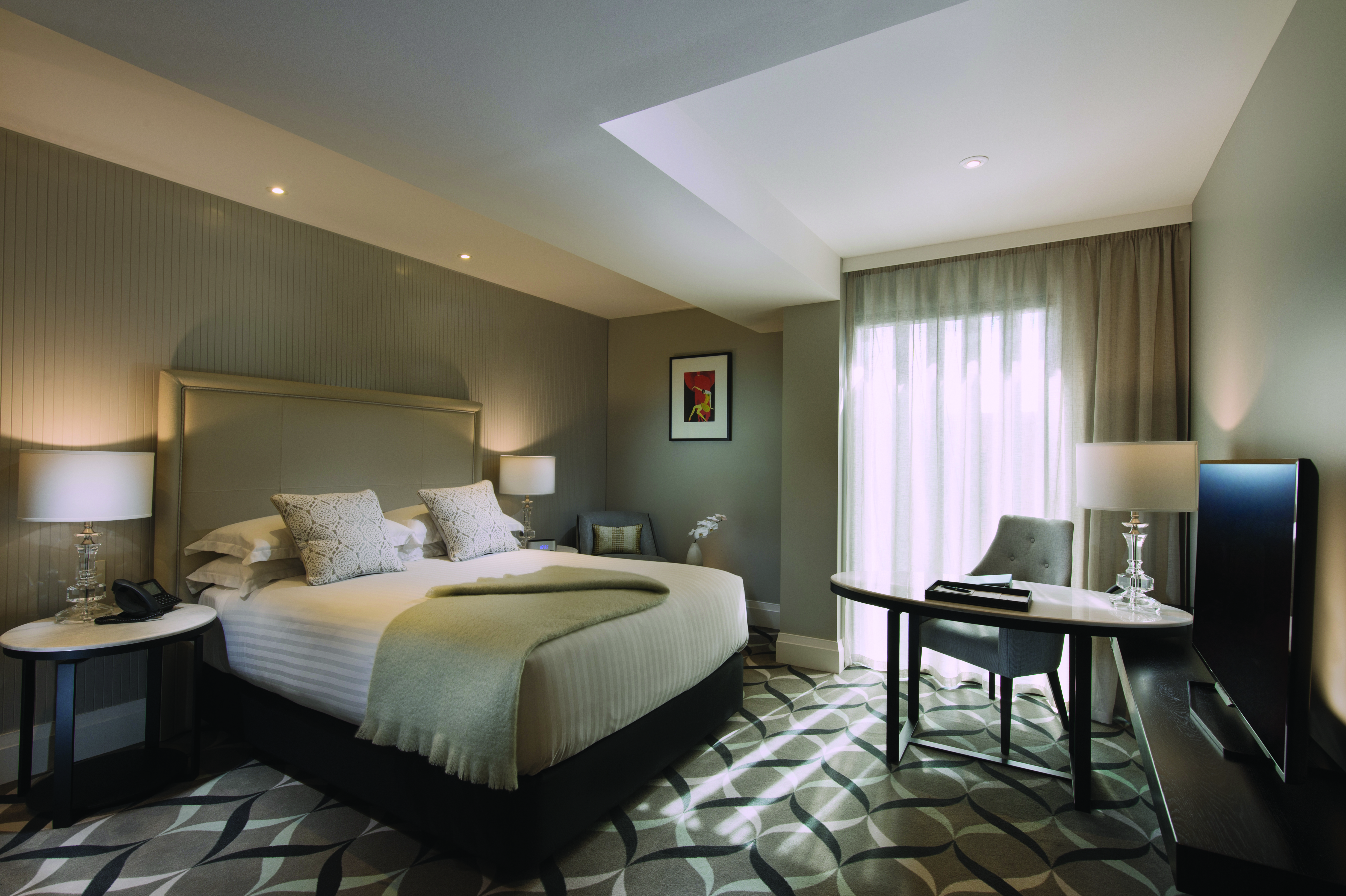 Superior queen room with large double bed, curtains, lamps and carpet