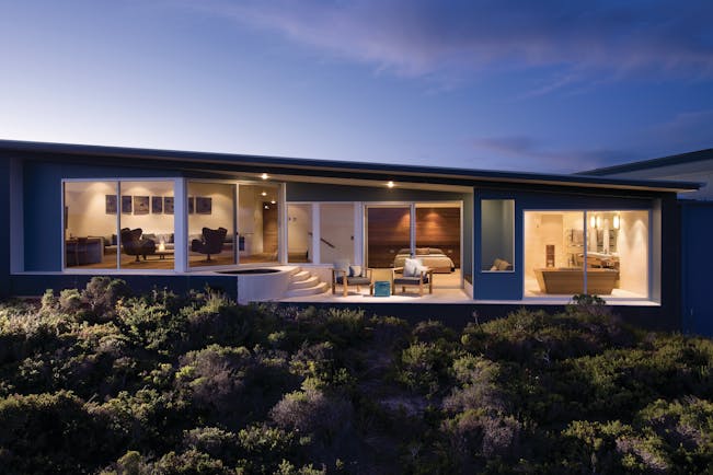 Exterior shot of the remarkable suite in Southern Ocean Lodge, long glass windows in bedroom, lounge and bathroom, private terrace with armchairs