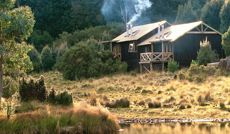 Cradle Mountain Lodge Tasmania exterior wood cabin surrounded by trees near water