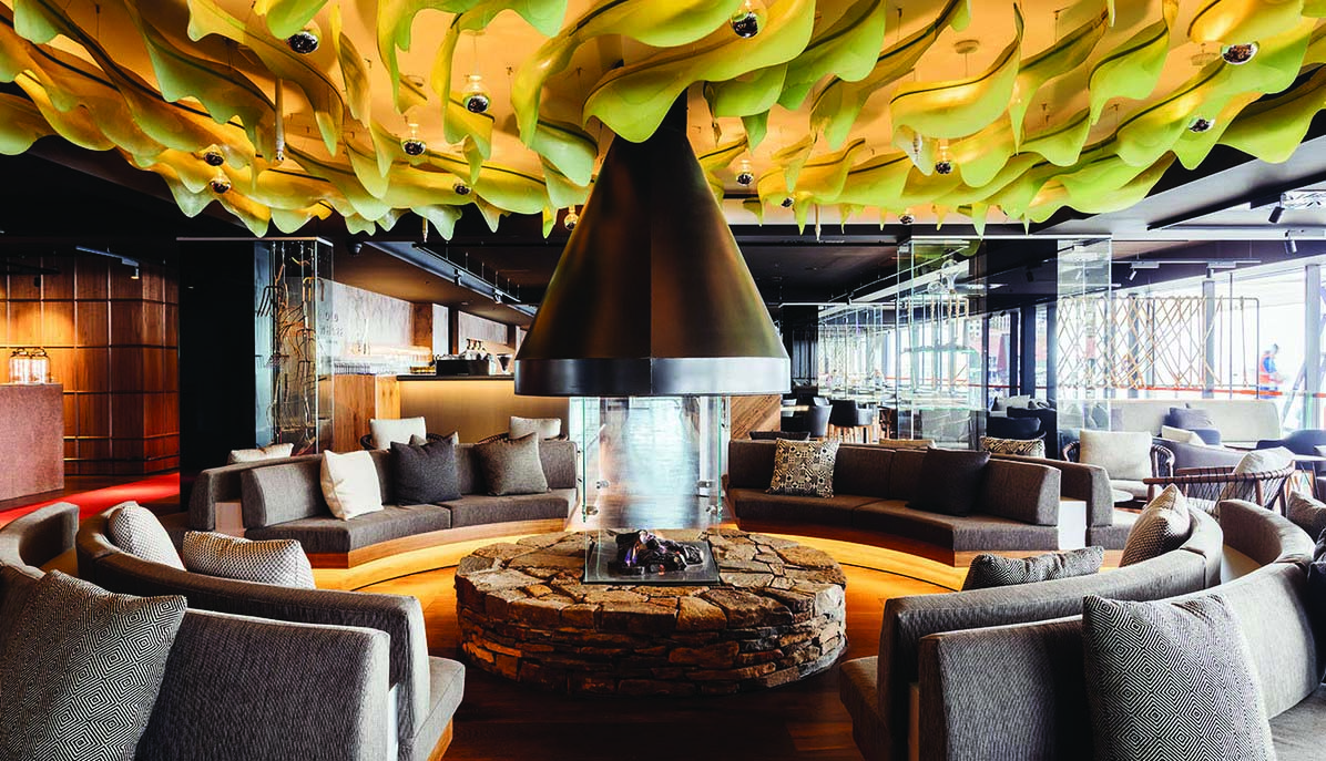 MACq01 bar, armchairs and sofas in communal seating area, central fireplace, modern decor and architecture