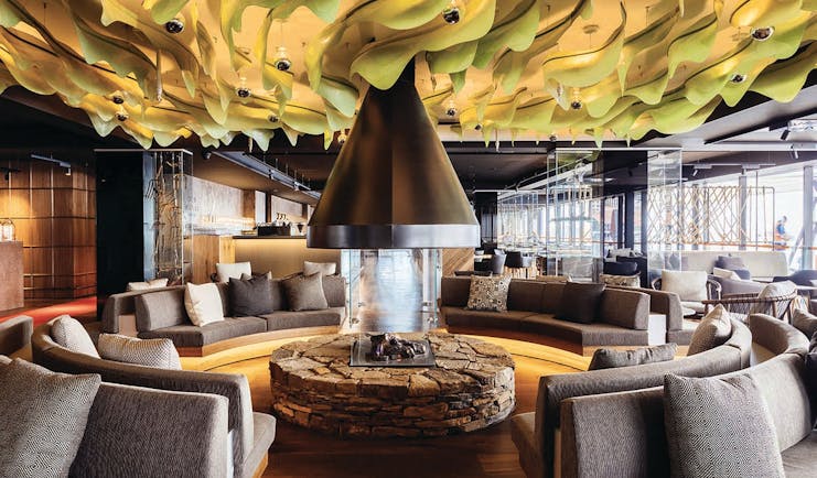 MACq01 bar, armchairs and sofas in communal seating area, central fireplace, modern decor and architecture