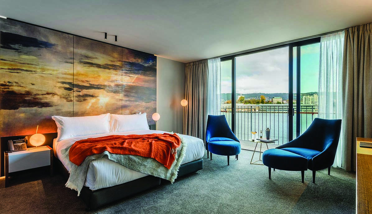 MACq01 guestroom, double bed, armchairs, modern decor with large painted sky mural wall, access to balcony overlooking marina