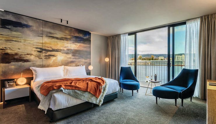 MACq01 guestroom, double bed, armchairs, modern decor with large painted sky mural wall, access to balcony overlooking marina