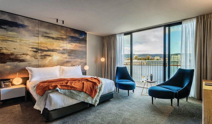 MACq01 guestroom, double bed, armchairs, modern decor with large painted sky mural wall, access to balcony overlooking marina