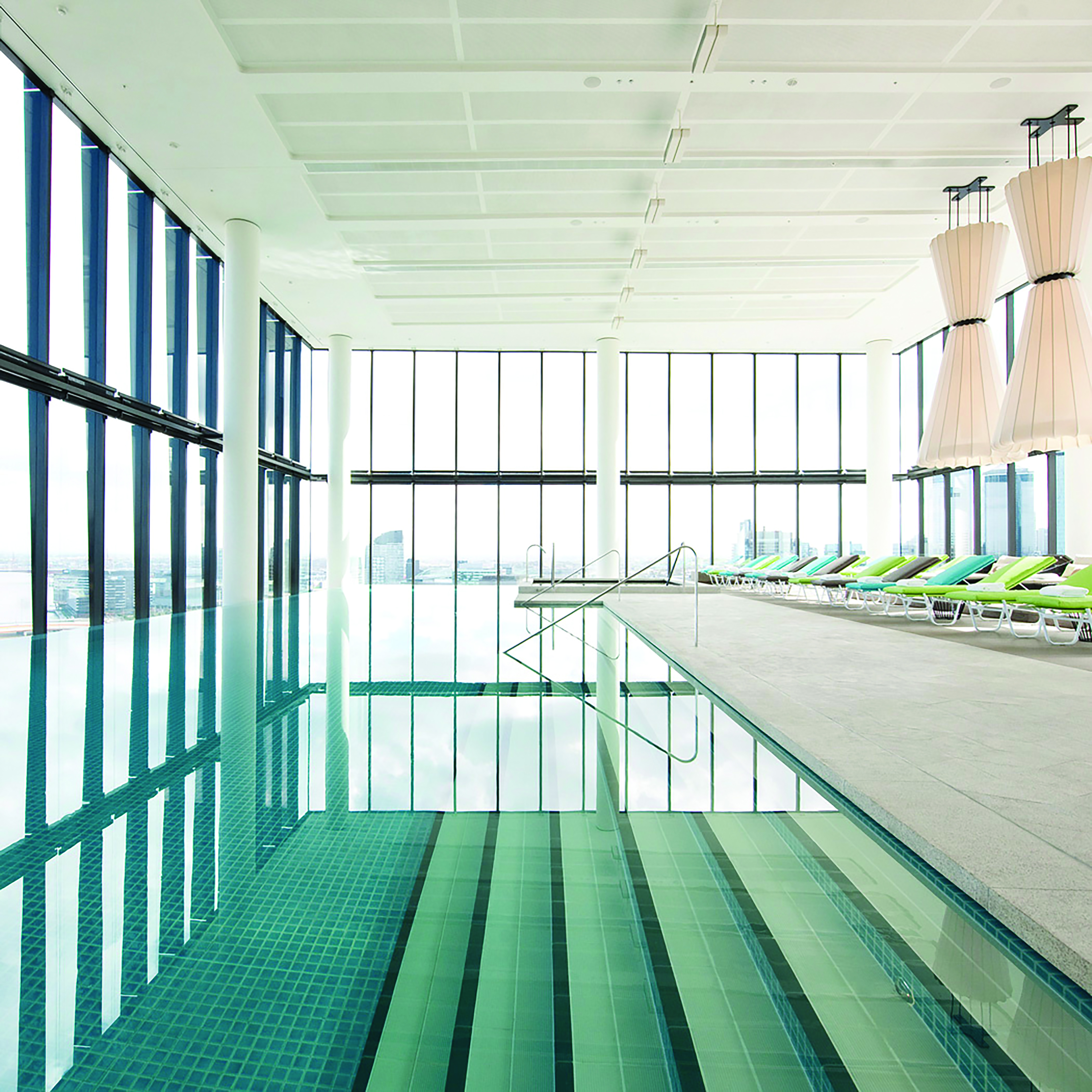 Indoor pool with window pannelled walls, and sun loungers surrounding the pool