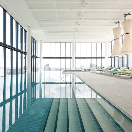 Indoor pool with window pannelled walls, and sun loungers surrounding the pool