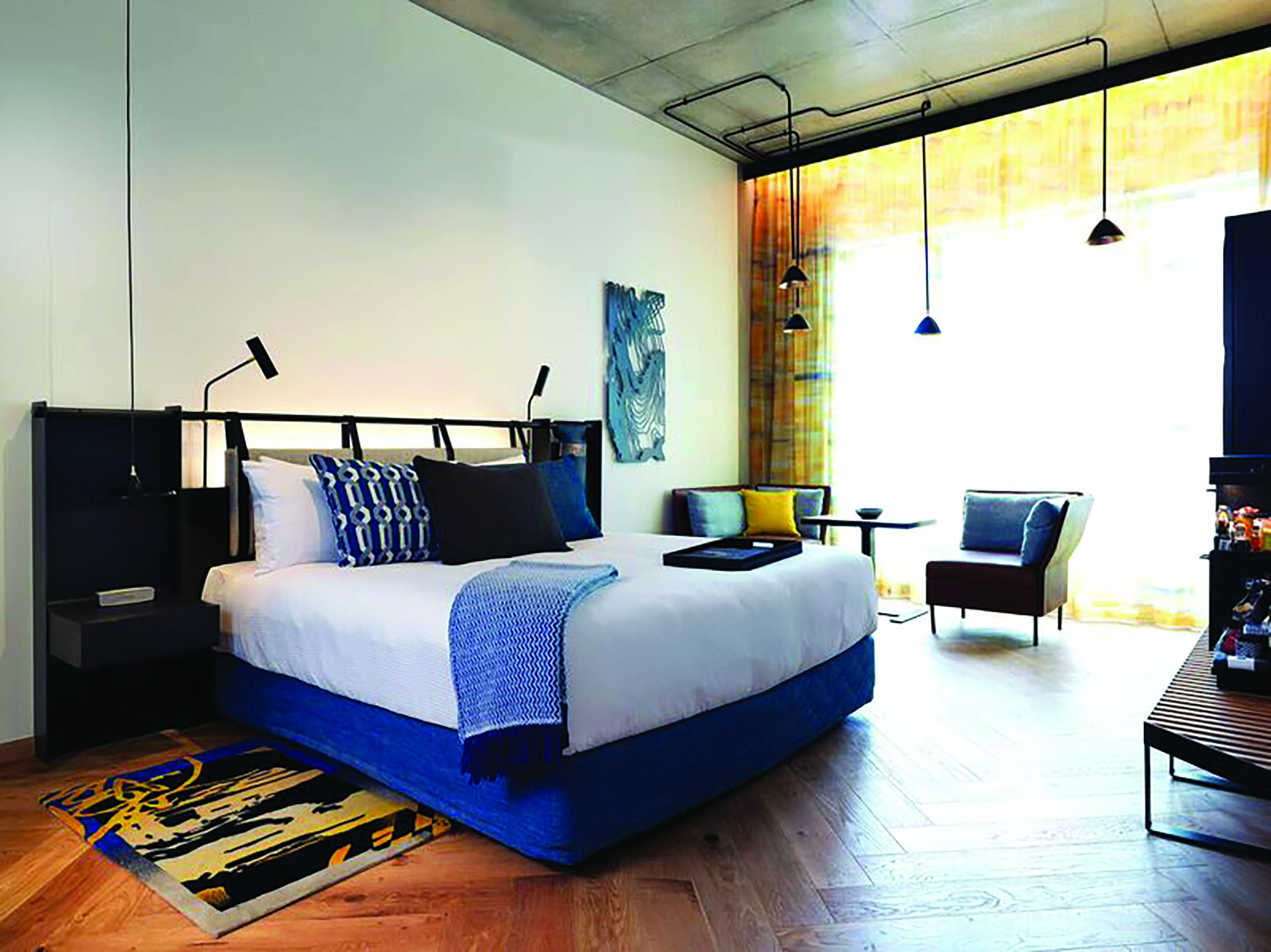 QT Melbourne executive room, bed, armchair, minimalist modern decor