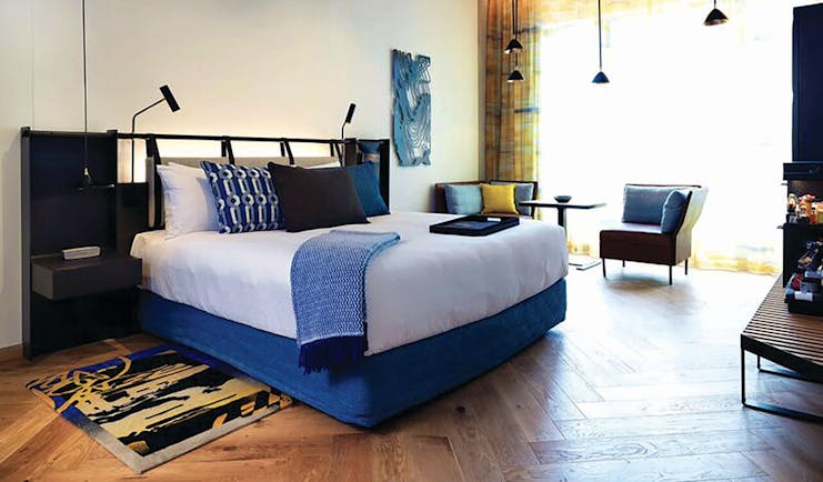 QT Melbourne executive room, bed, armchair, minimalist modern decor
