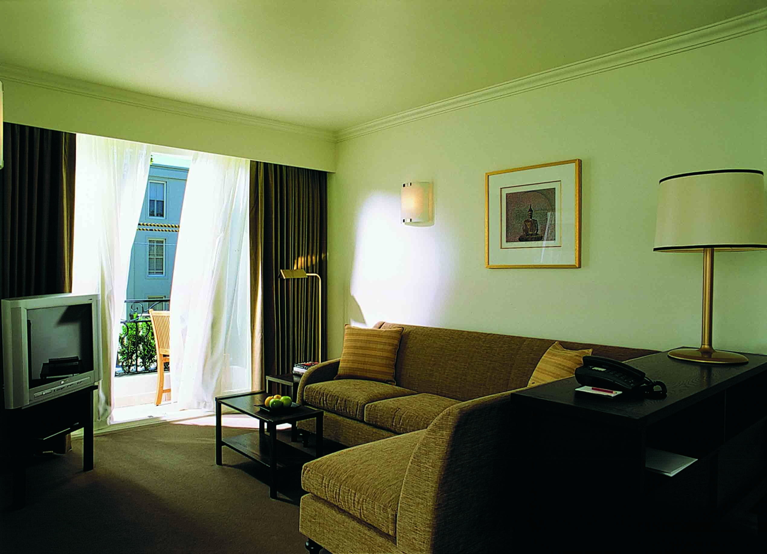 The Lyall Hotel Melbourne living room with sofas and television and doors to balcony with chair