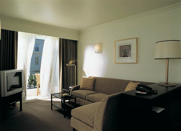The Lyall Hotel Melbourne living room with sofas and television and doors to balcony with chair
