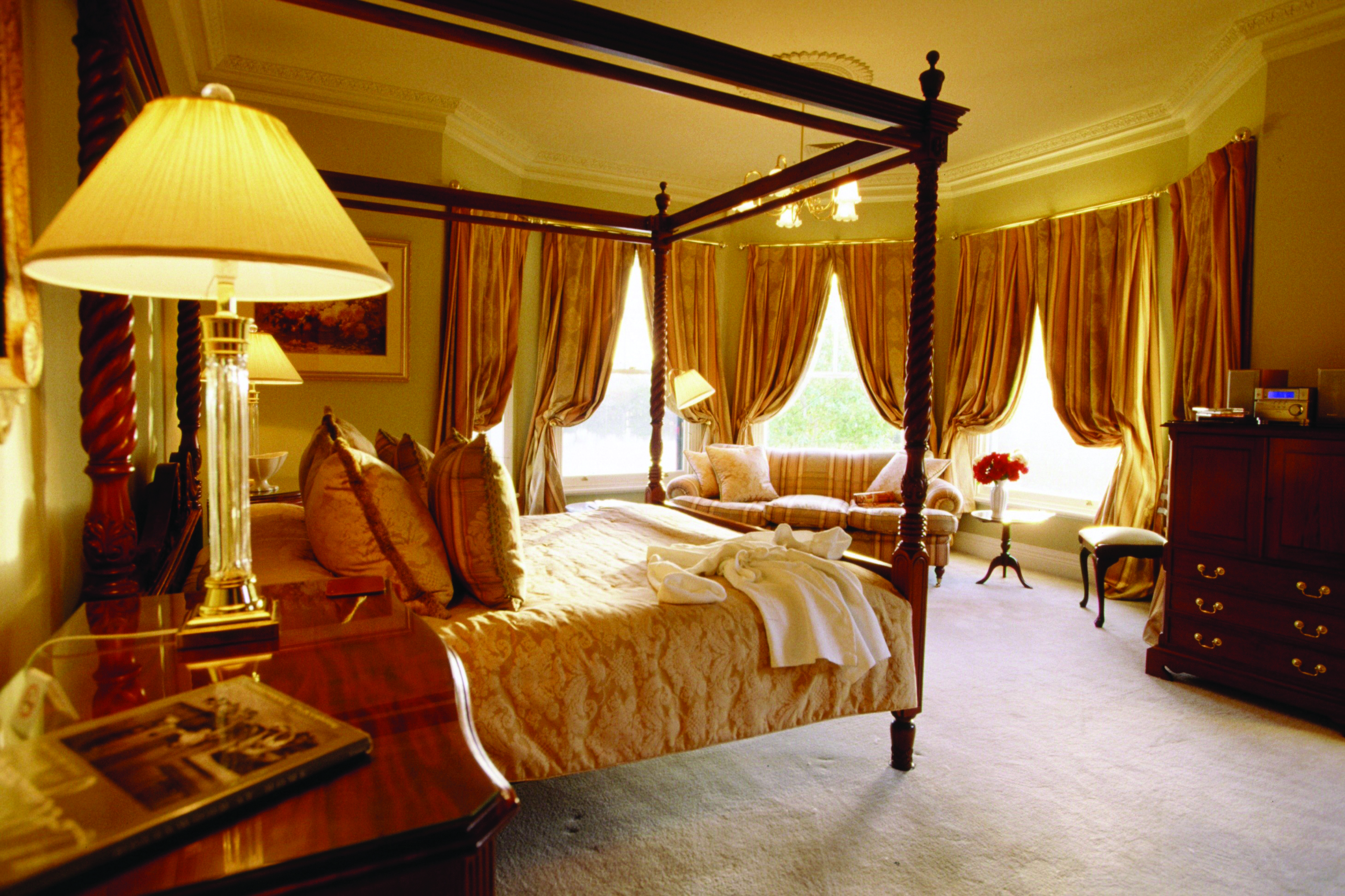 Woodman Estate Victoria Manor House lake suite bedroom with four poster bed sofa and large windows with drapes