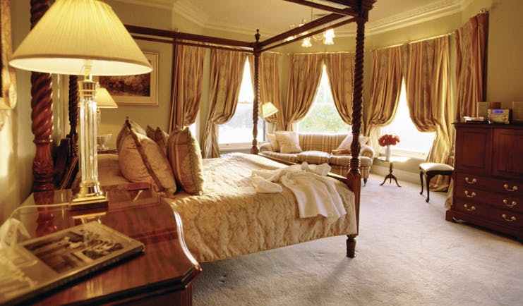 Woodman Estate Victoria Manor House lake suite bedroom with four poster bed sofa and large windows with drapes