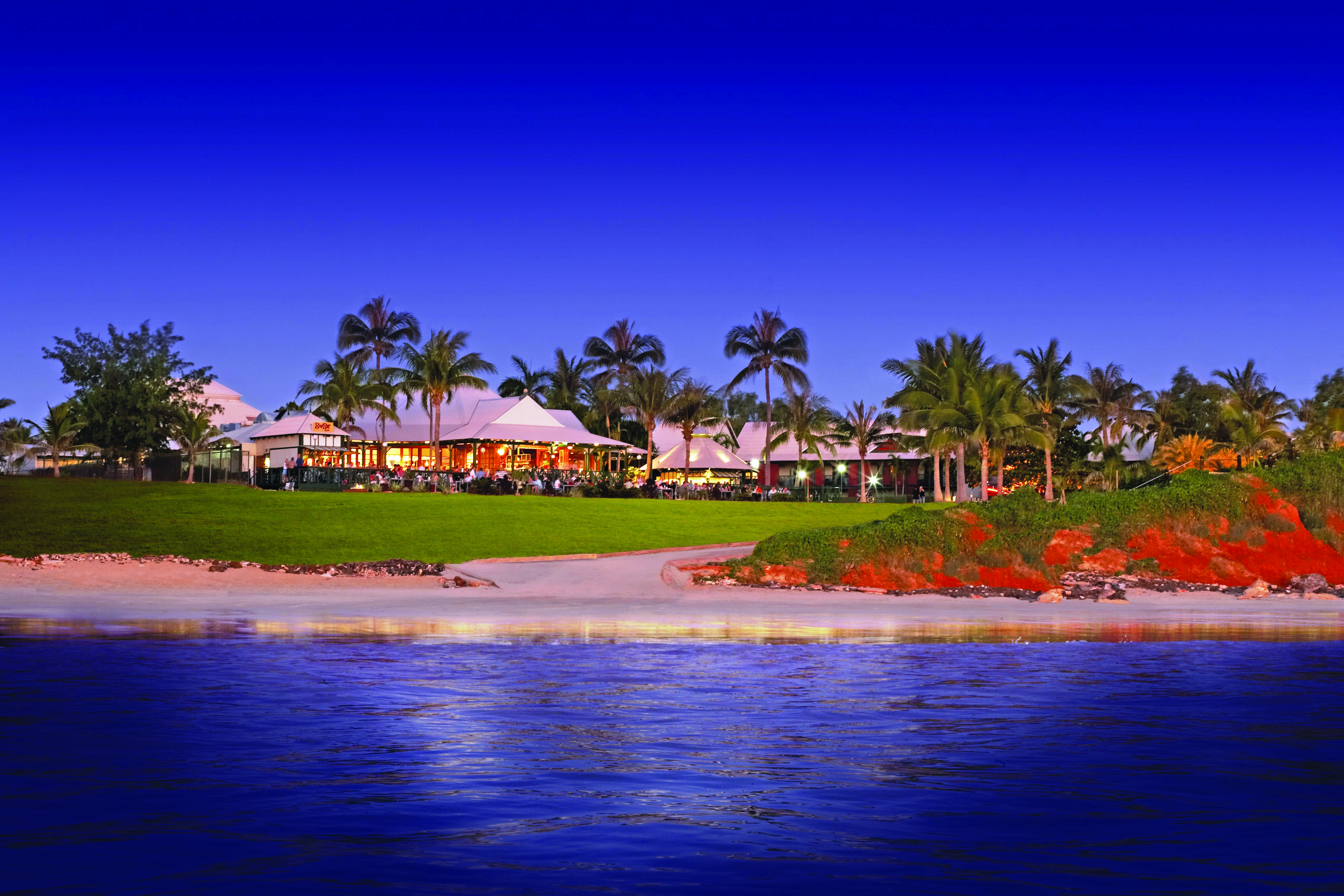 Cable Beach Club exterior shot from sea, hotel buildings, green lawns, palm trees, sand, sea