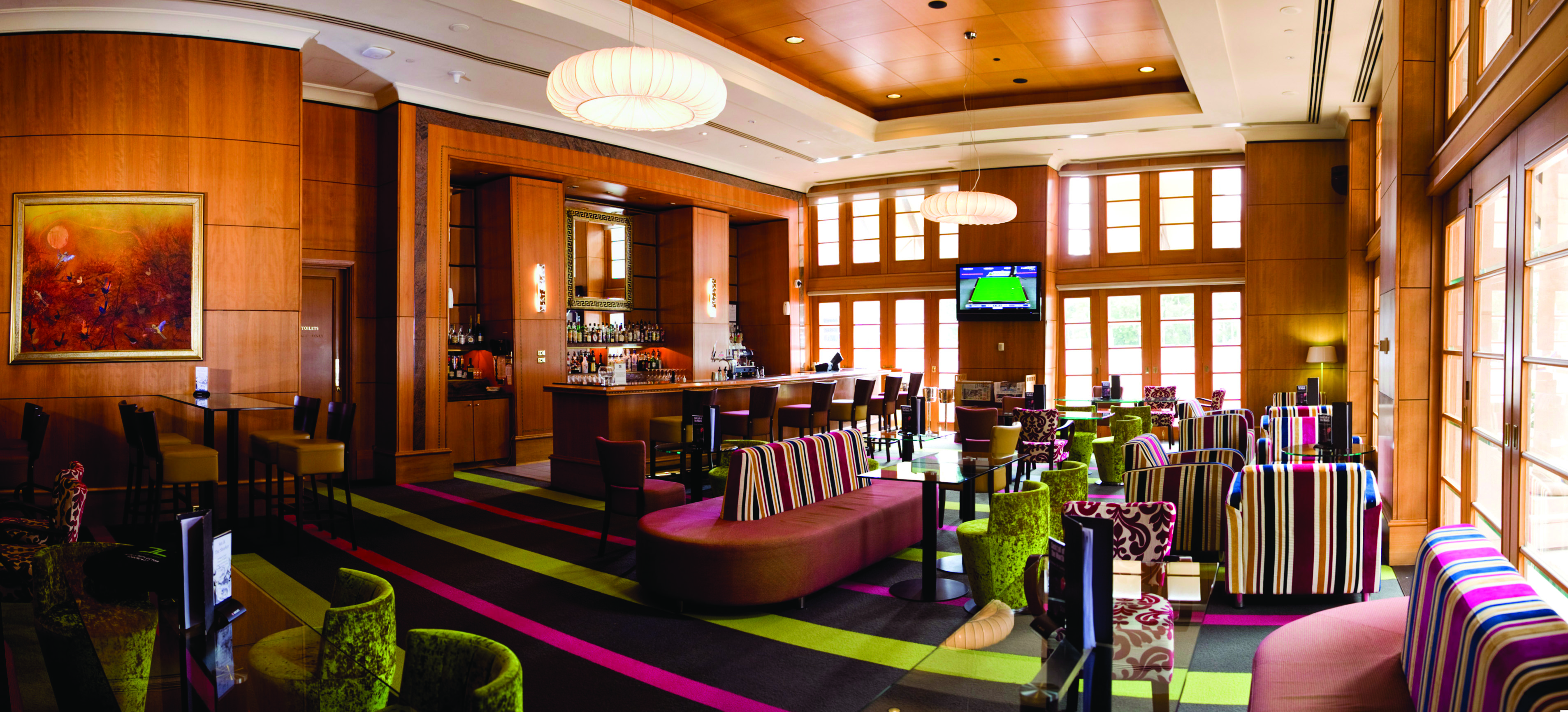 Duxton Hotel Western Australia and Perth lobby bar area with striped chairs and televisions