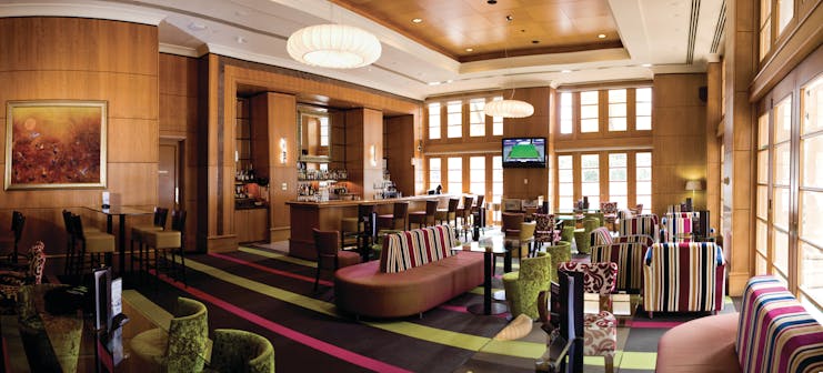 Duxton Hotel Western Australia and Perth lobby bar area with striped chairs and televisions