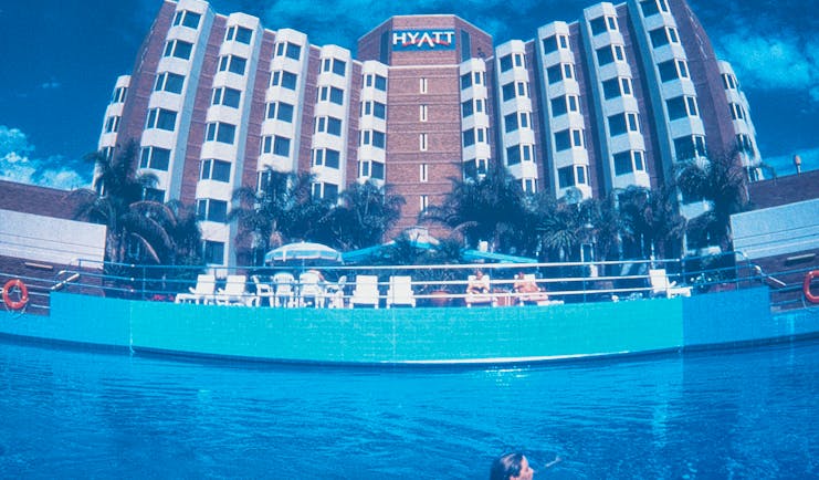 Exterior of hotel and swimming pool with building saying 