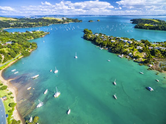 Putaki Bay in Waiheke Island near Auckland, bright blue ocean, boats on water, coastline