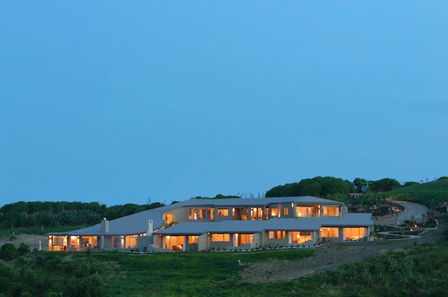 Exterior of hotel at night with white roof and window lights lighting up the hotel 