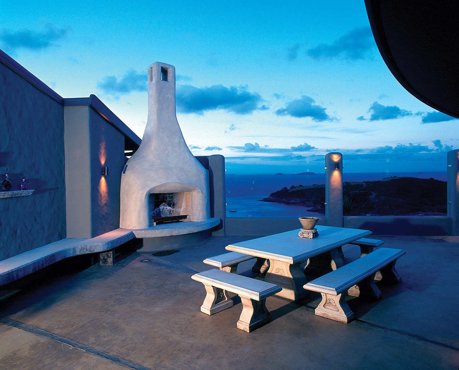 Outdoor terrace fireplace area with bench, fireplace and view over the sea