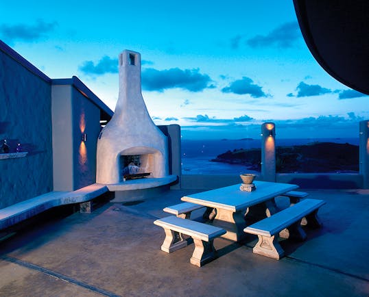 Outdoor terrace fireplace area with bench, fireplace and view over the sea