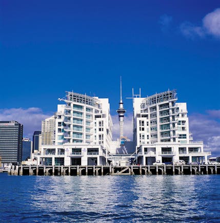 View of exterior of hotel with sea in front and white hotel building shown on edge