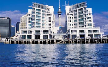 View of exterior of hotel with sea in front and white hotel building shown on edge