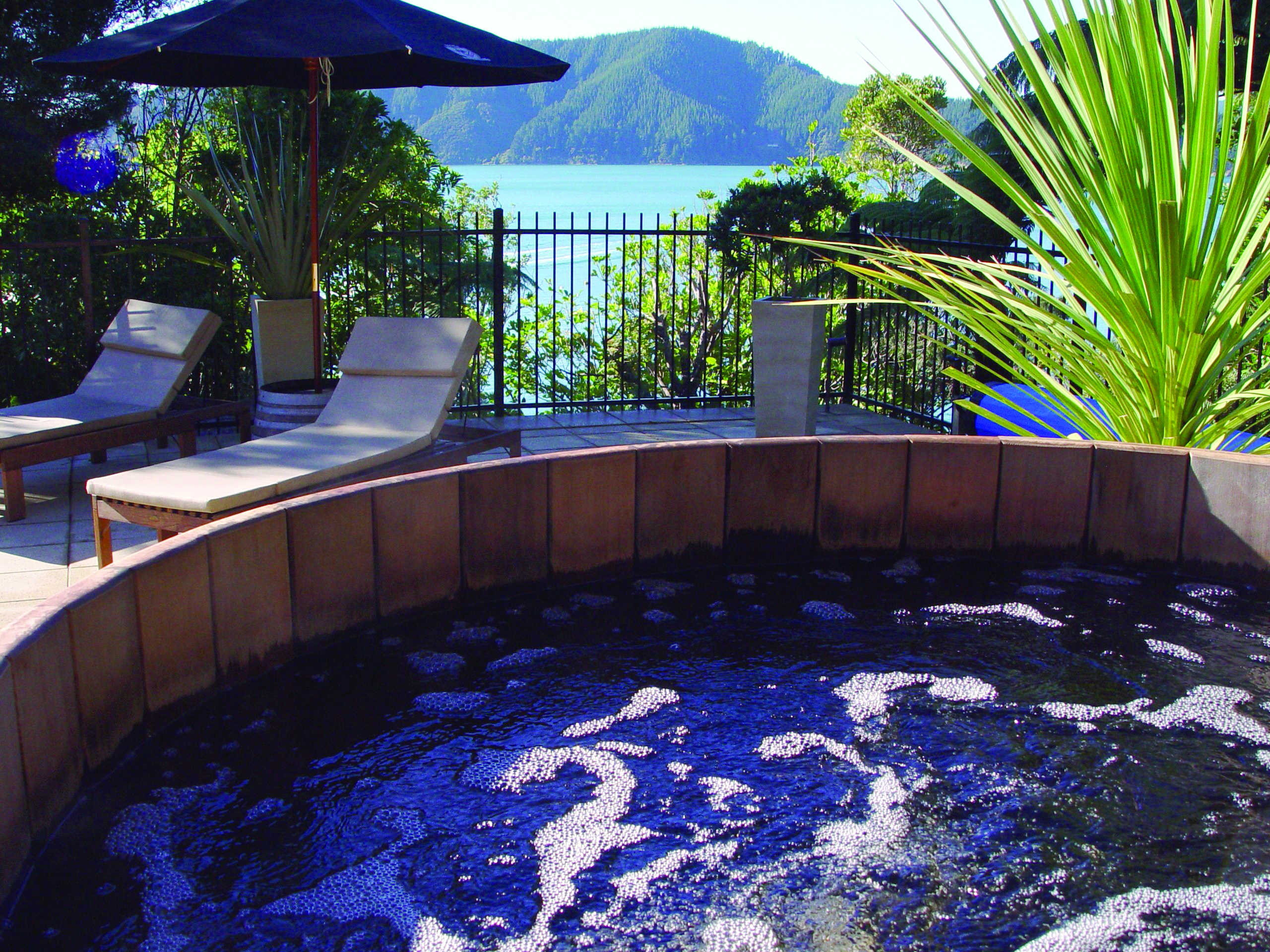 Jacuzzi on patio with deck chairs on looking out over sea