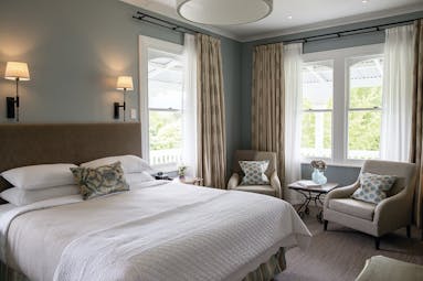 Marlborough Lodge Blenheim and Marlborough premium suite bedroom with two armchairs and porch view
