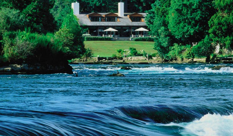 Huka Lodge Central North Island exterior view over river rapids to lodge and gardens