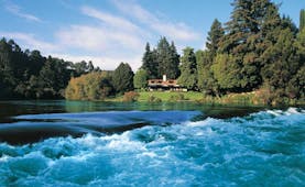 Huka Lodge Central North Island falls aerial view of a lodge and gardens surrounded by trees near river with rapids